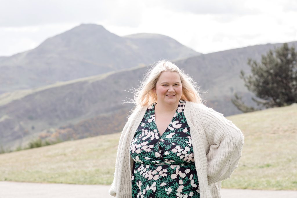 lady in a green floral dress in front of hills