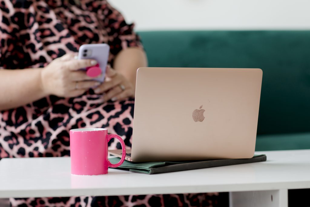 close up of a laptop with a woman on her phone behind it