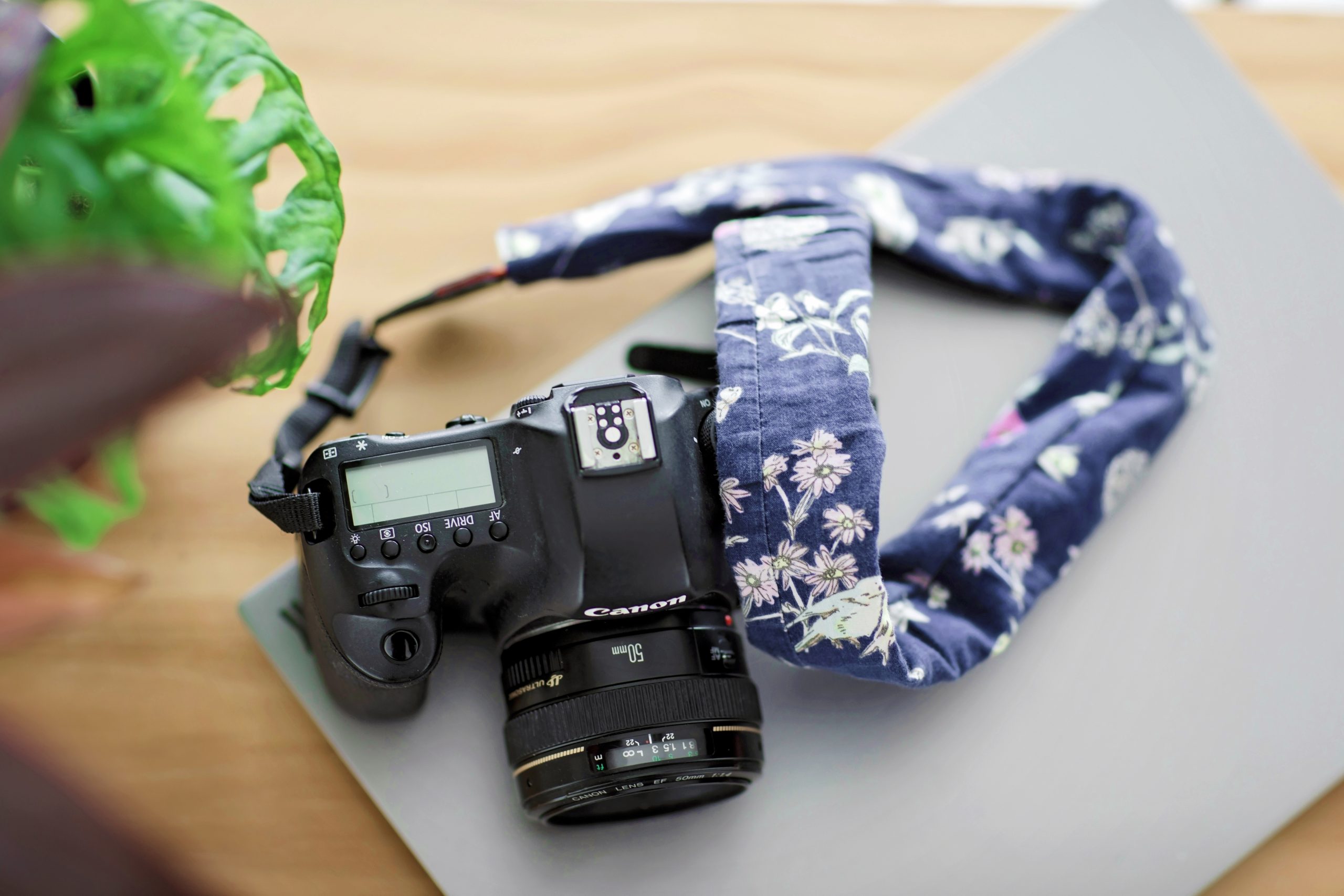 image of canon camera with floral strap on a closed laptop