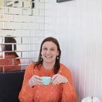 lady laughing in a cafe with a coffee