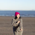 lady laughing on the beach, blue skies, bright pink hat