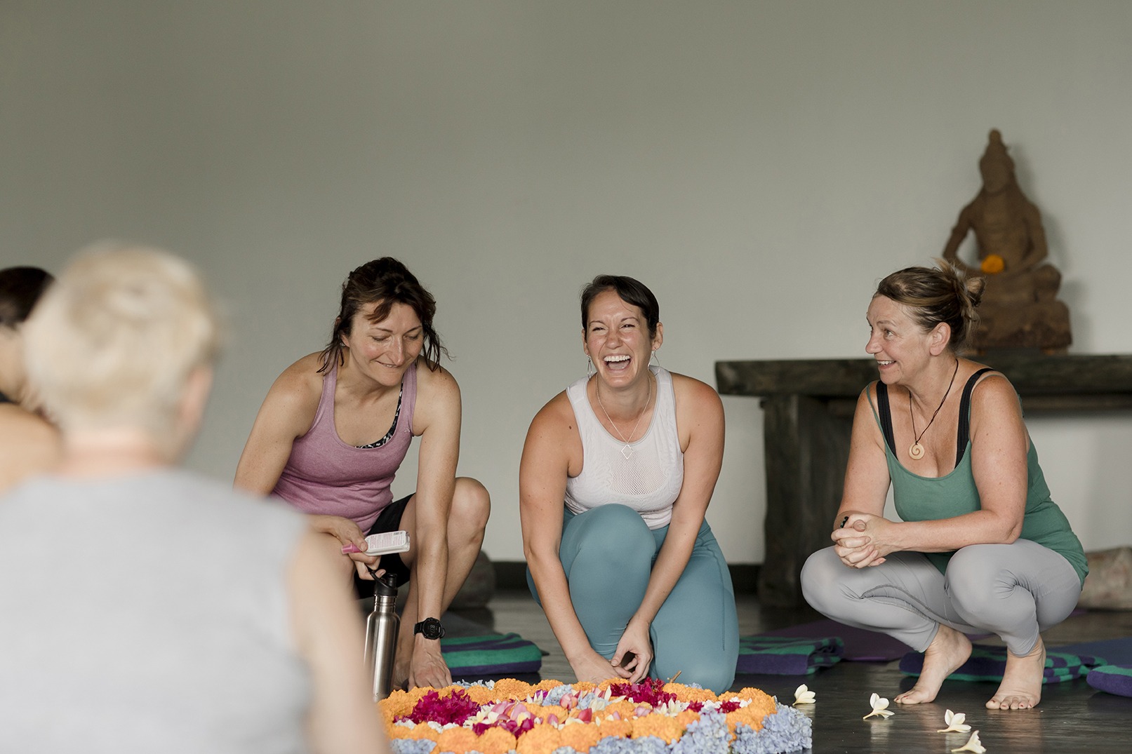 yoga teacher laughing with her students around a floral arrangment in Bali