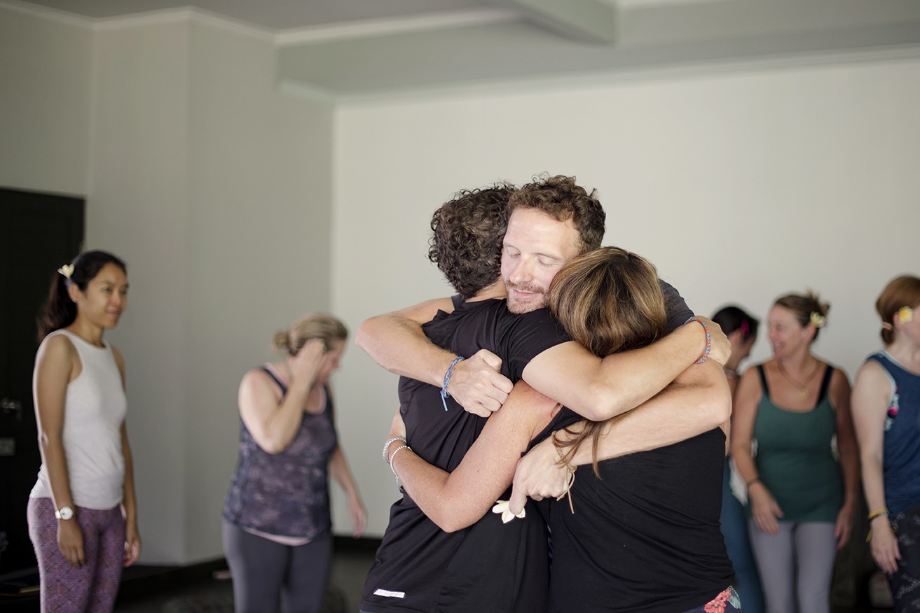 three people embrace at a yoga retreat