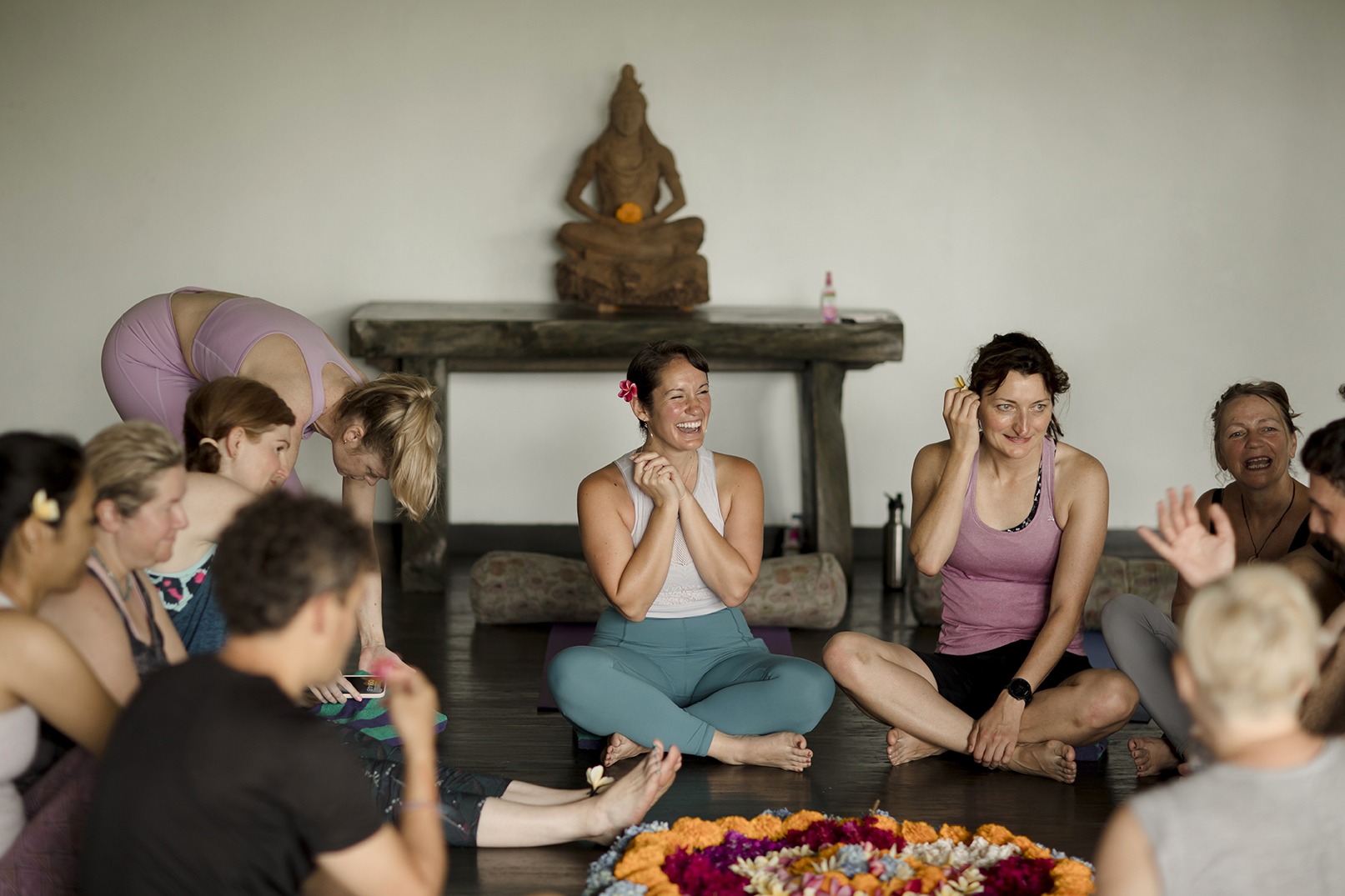 yoga teacher laughing with her students around a floral arrangment in Bali