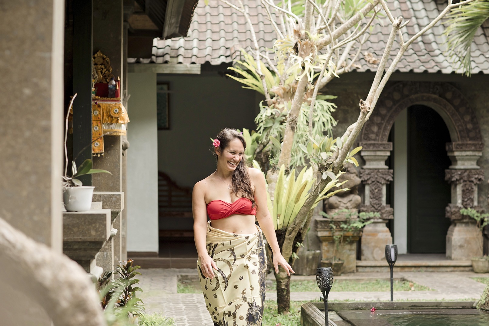 portrait of a lady laughing as she walks beside a swimming pool at a yoga retreat in Bali