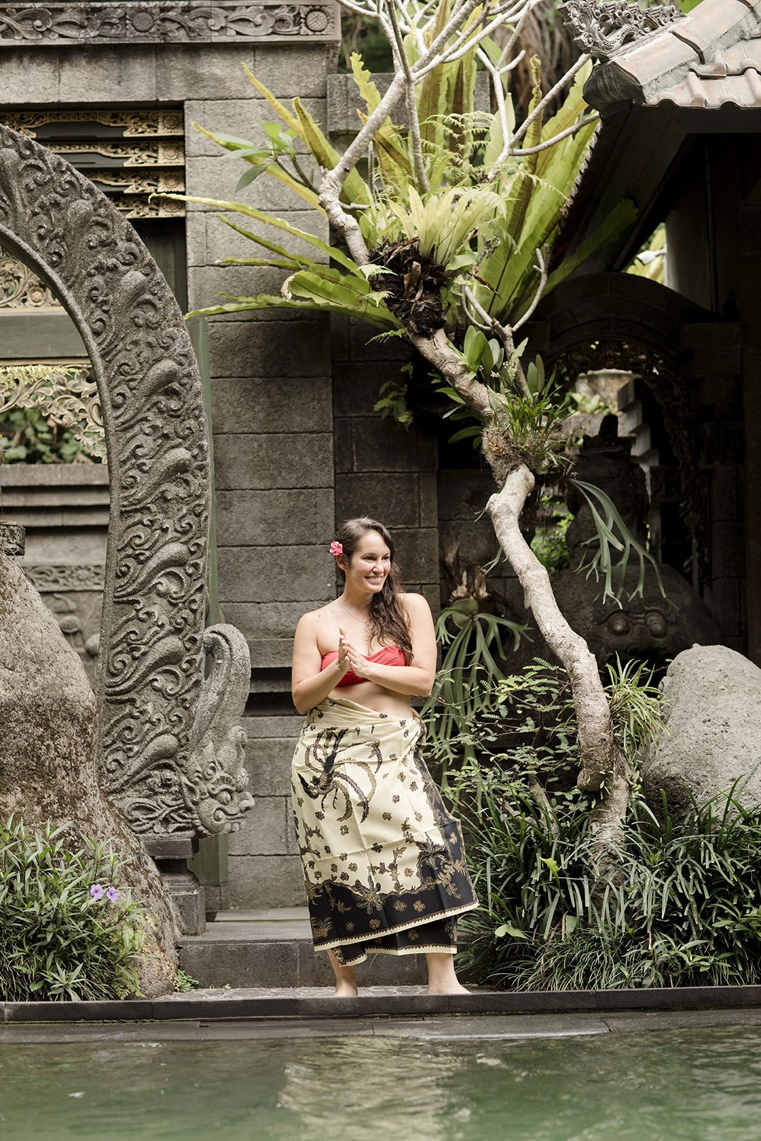 portrait of a lady laughing as she walks beside a swimming pool at a yoga retreat in Bali
