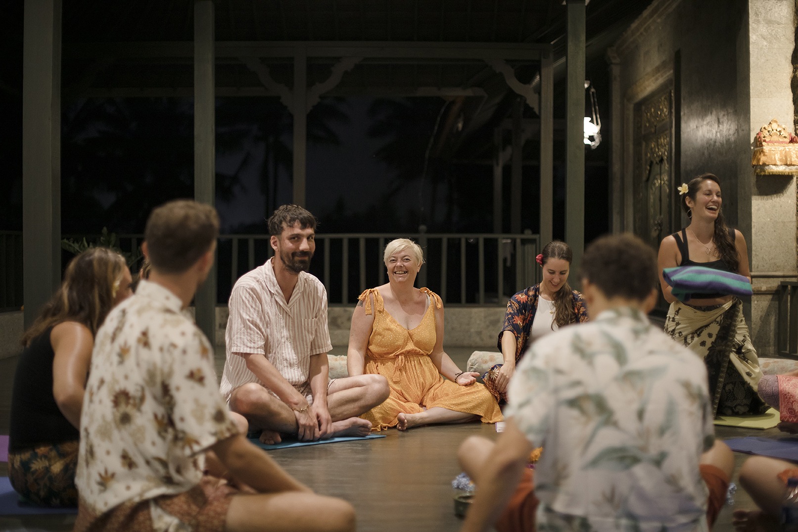 yoga teacher laughing with her students around a floral arrangement in Bali