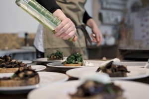 chef pouring oil over plate of food