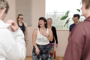 yoga teacher laughing with students in yoga barn