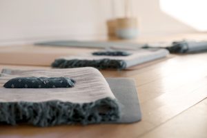 yoga mats and blankets piled up on wooden floor