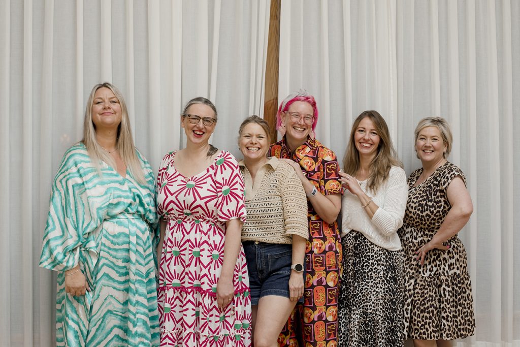 group of business owners on a sales retreat in lanzarote - they are standing against a white curtain smiling and laughing